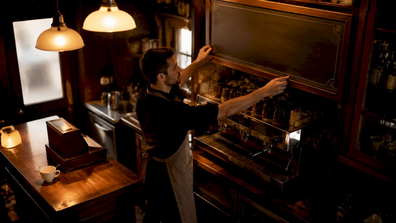 Cafe owner adjusting menu board above counter