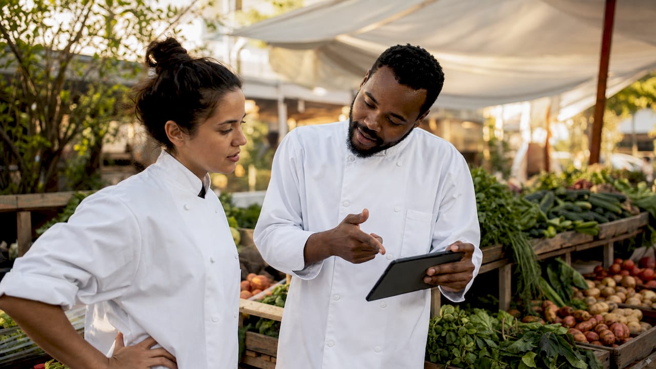 Two chefs coordinating virtual restaurant orders in kitchen