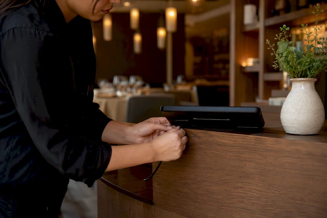 Hands plugging charger into restaurant tablet