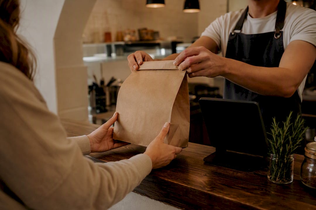 Hands exchanging food pickup bag at counter