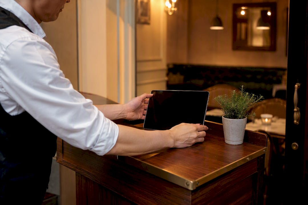 Host setting down dark tablet at restaurant podium