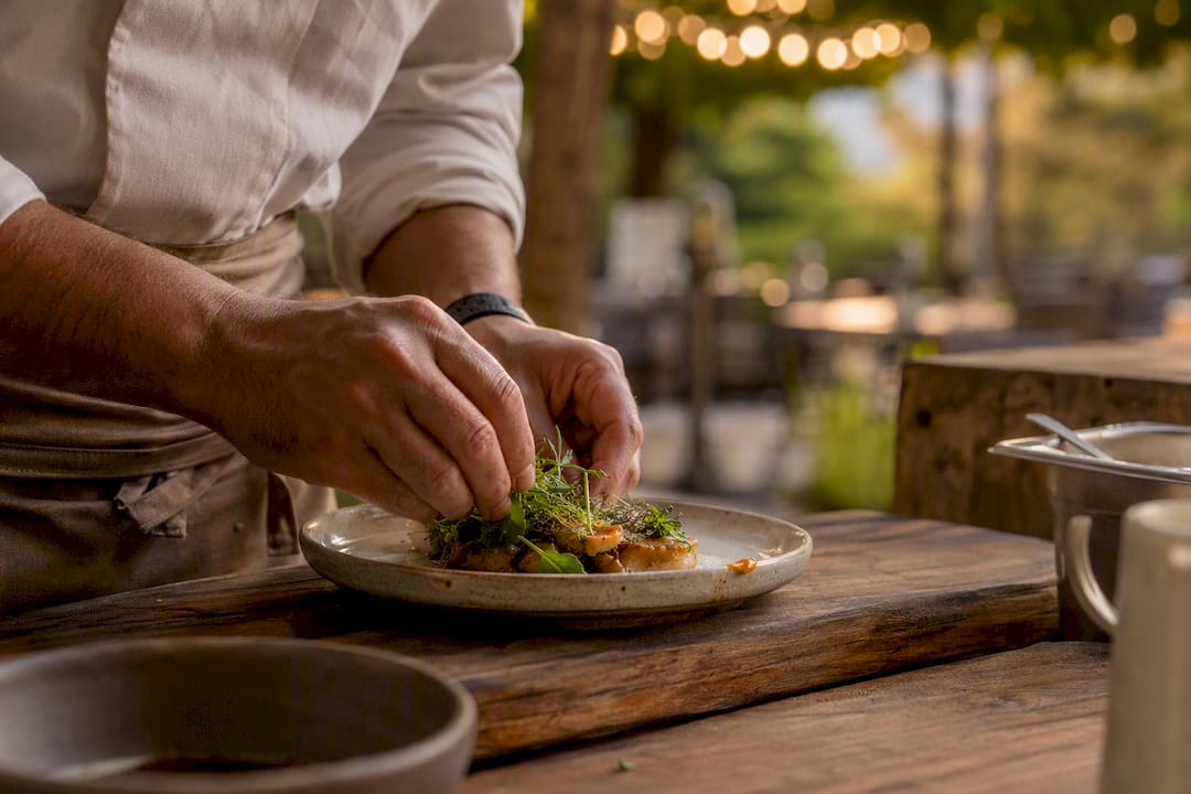 Server hands wrapping food order in kitchen