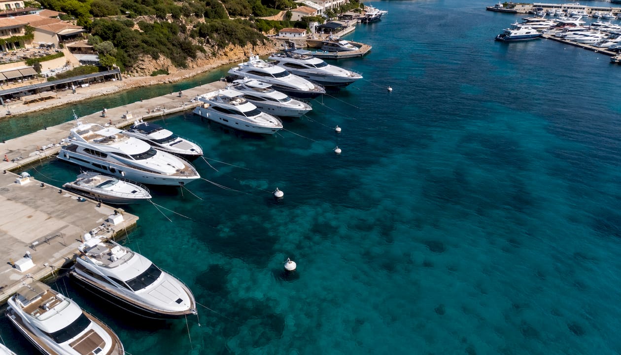 Eleganti yacht ormeggiati a Porto Cervo, illuminati dai caldi colori del tramonto.