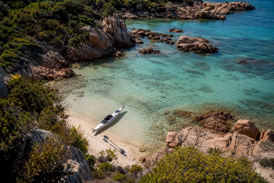 Attrezzatura da kayak sistemata sulla spiaggia di una caletta a La Maddalena