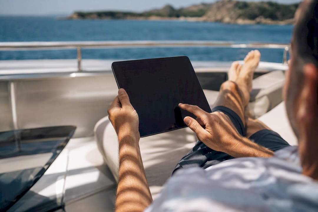 Guest holding tablet on yacht deck