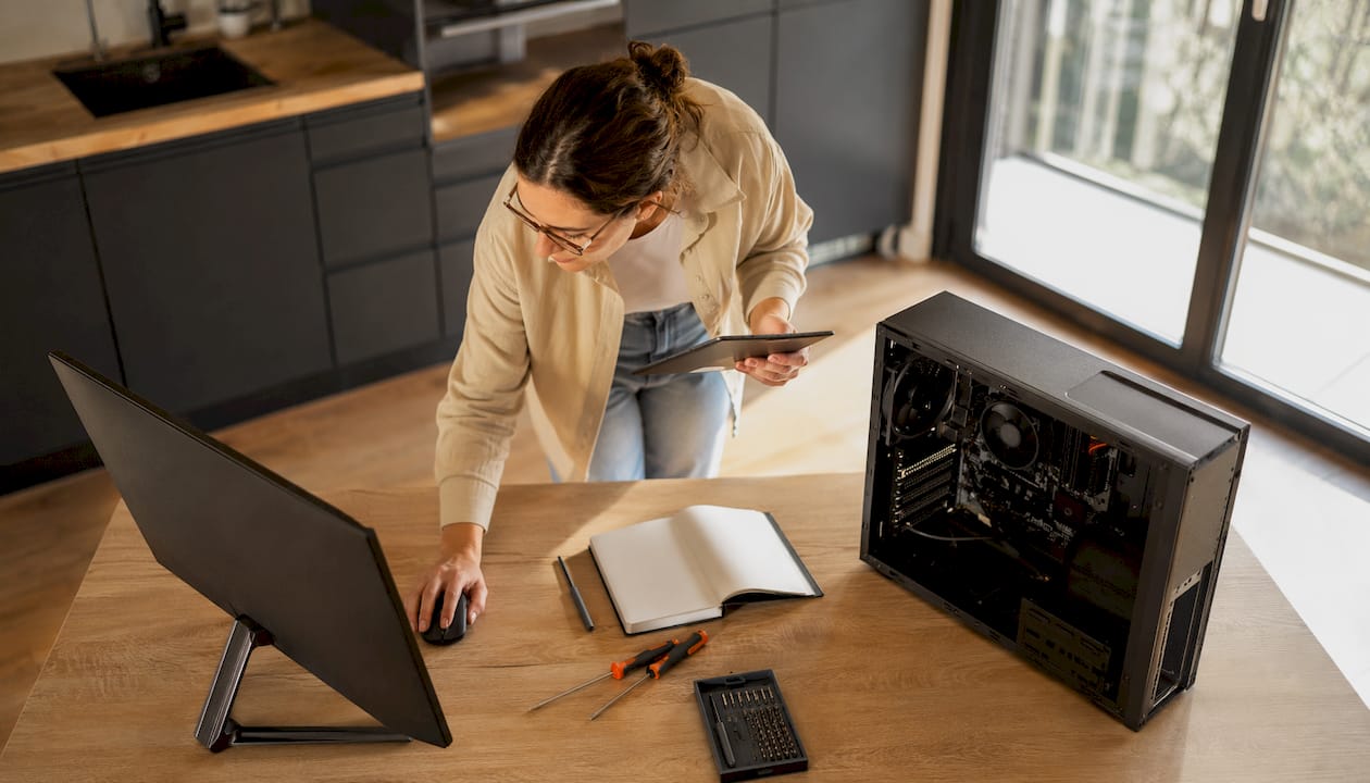 Une femme assise à son bureau examine son ordinateur pour identifier ce qui ralentit ses performances.