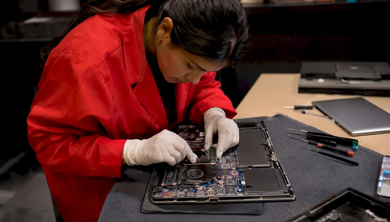 Une technicienne procède à l’installation d’un SSD NVMe dans un ordinateur portable.