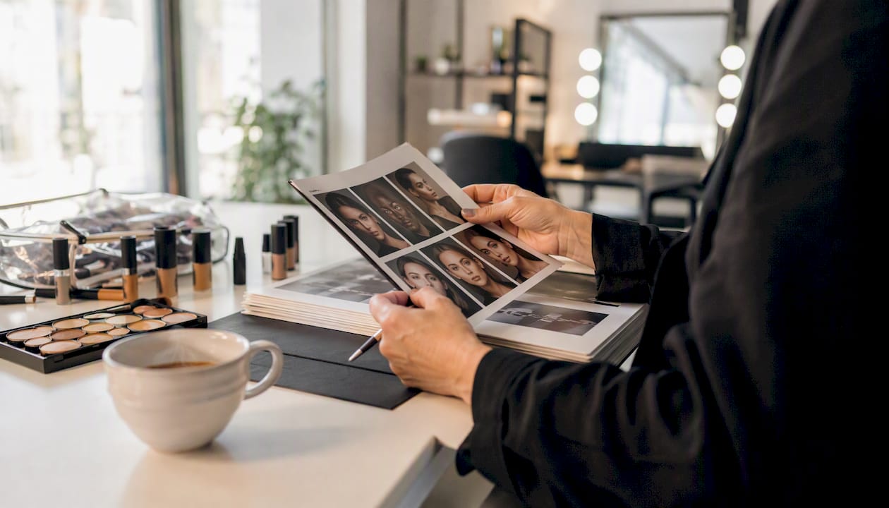 Le mani del make-up artist scorrono tra le pagine del catalogo dei volti da truccare.