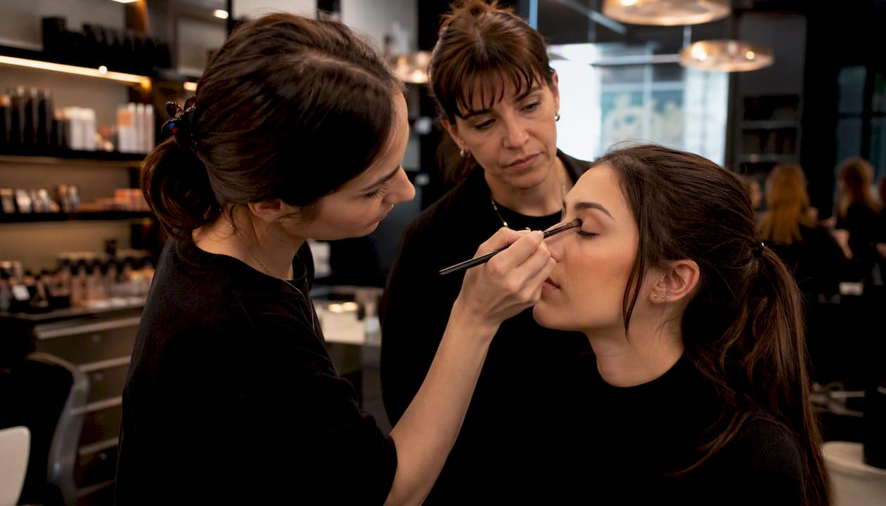 Tirocinante che si esercita nell’applicazione del trucco durante uno stage in una profumeria