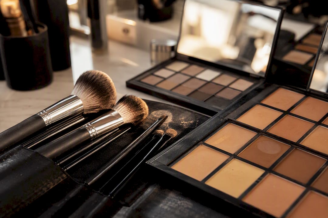 Pennelli da trucco e palette neutre sulla scrivania