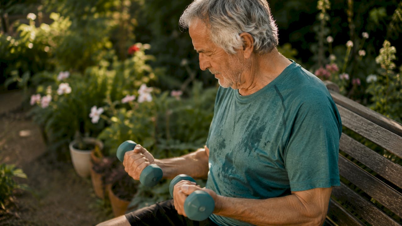 Elderly man lifting dumbbells indoors