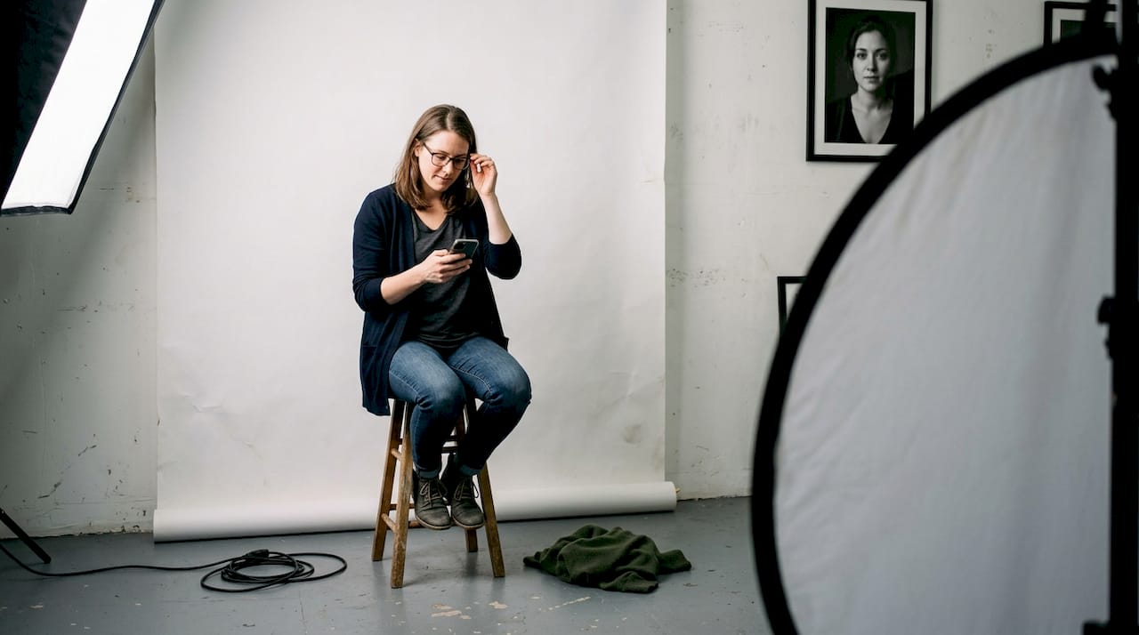 Mujer posando en un estudio fotográfico con un fondo neutro.