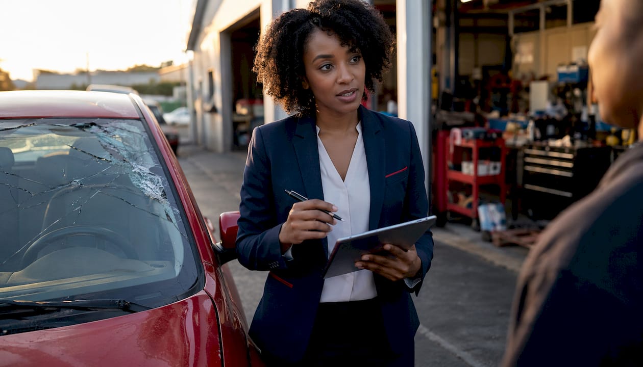 Insurance agent assessing windshield damage outdoors
