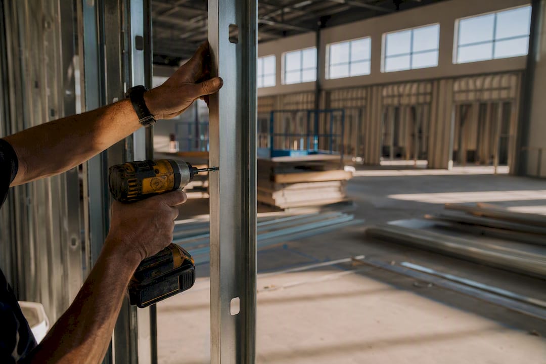 Hands installing interior framing during warehouse fit-out