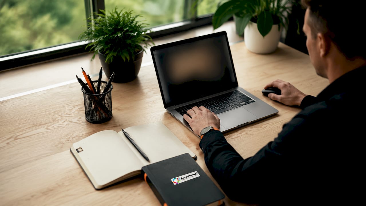 Een hand stuurt de muis naast het laptopscherm.