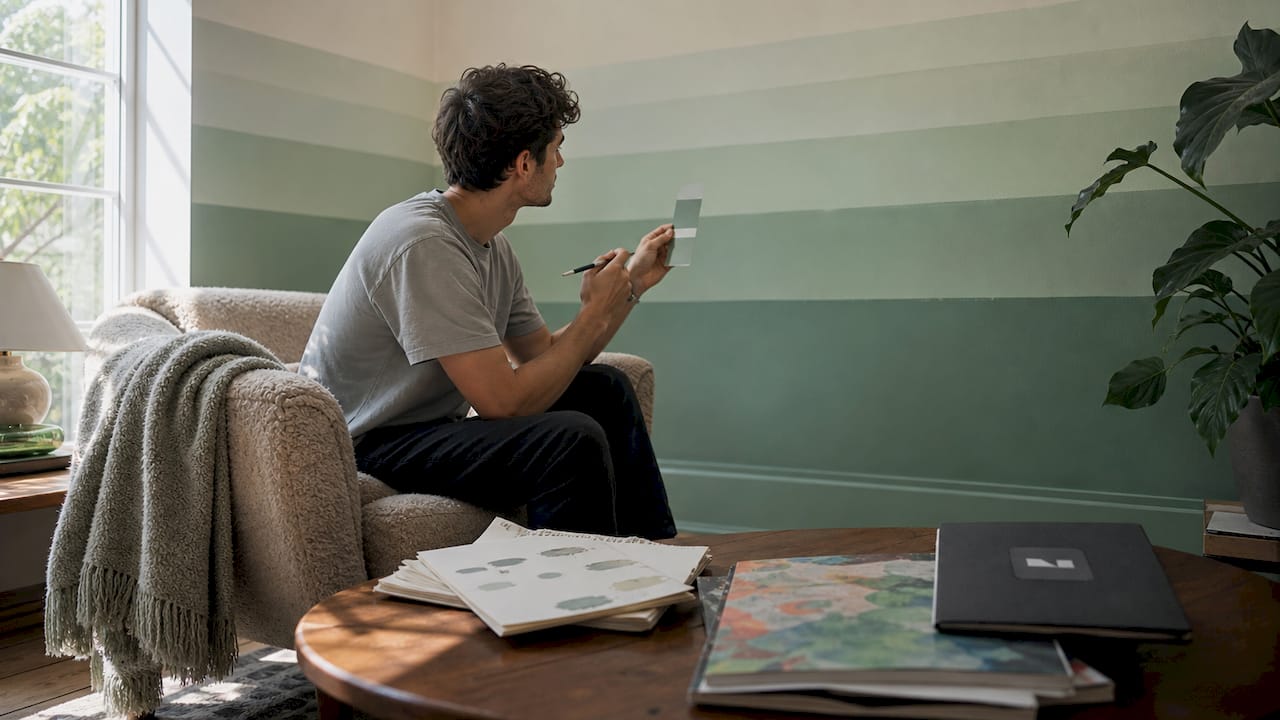 Young man examining painted gradient bedroom wall