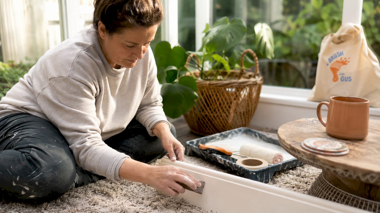 Woman sanding skirting boards before painting