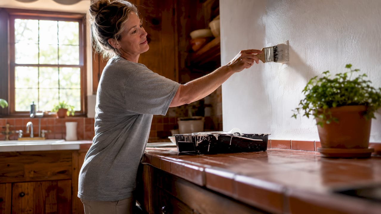 Homeowner applying paint primer to wall