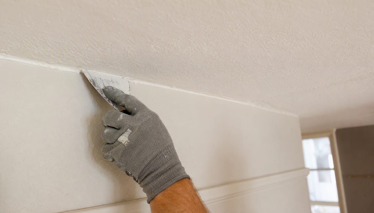 Hand filling wall crack with flexible caulk