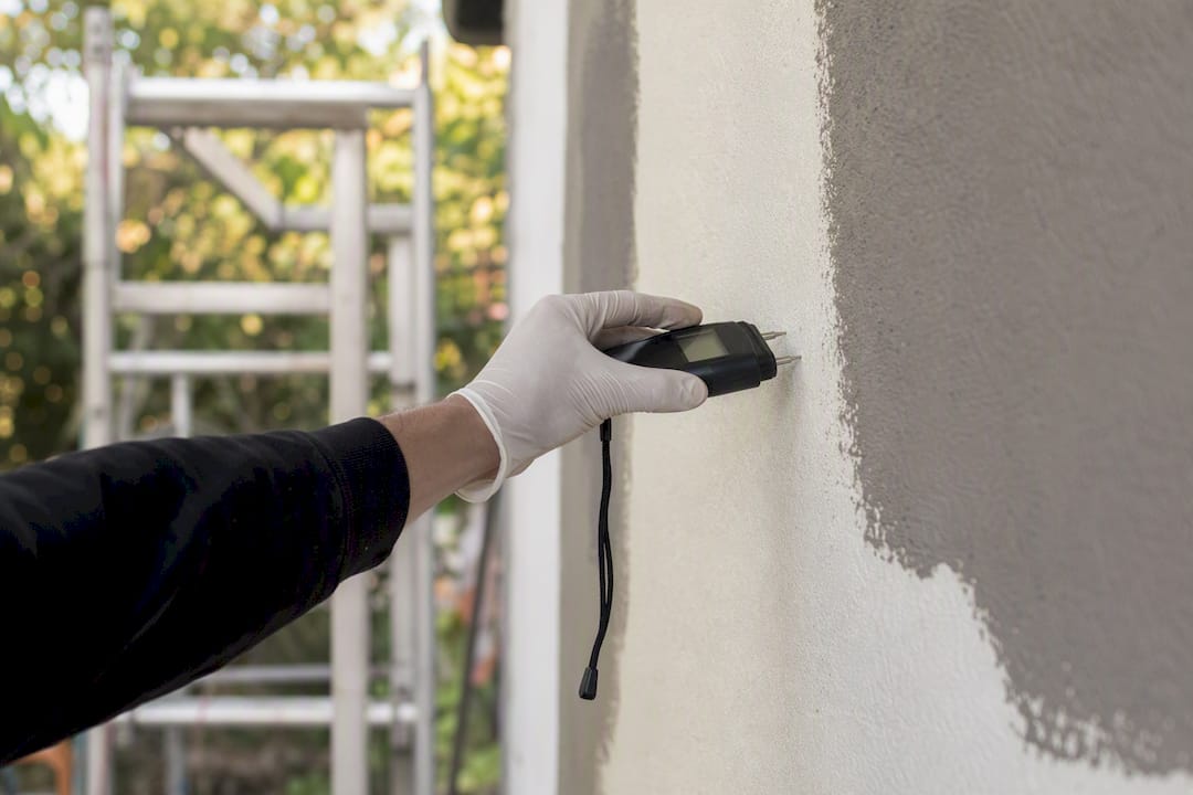 Moisture meter testing on exterior render wall