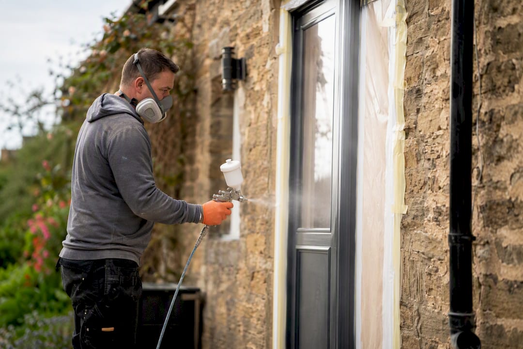 Spray painter applying paint in dry mild weather