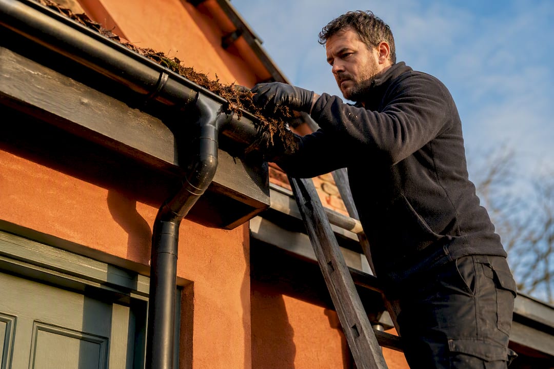 Professional cleaning a UK home's gutter