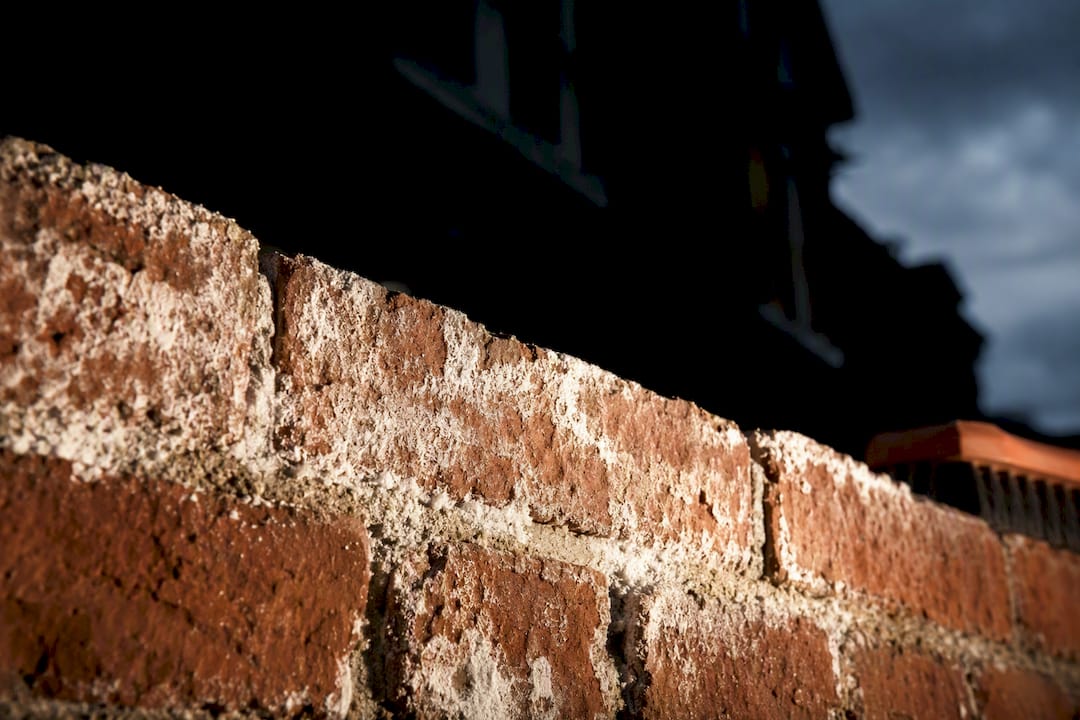 White efflorescence deposits on brick wall