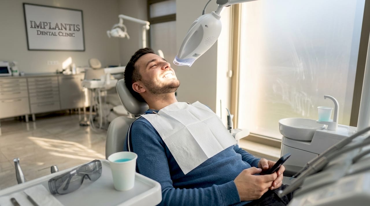 Pacjent poddawany wybielaniu zębów przy użyciu lampy stomatologicznej.