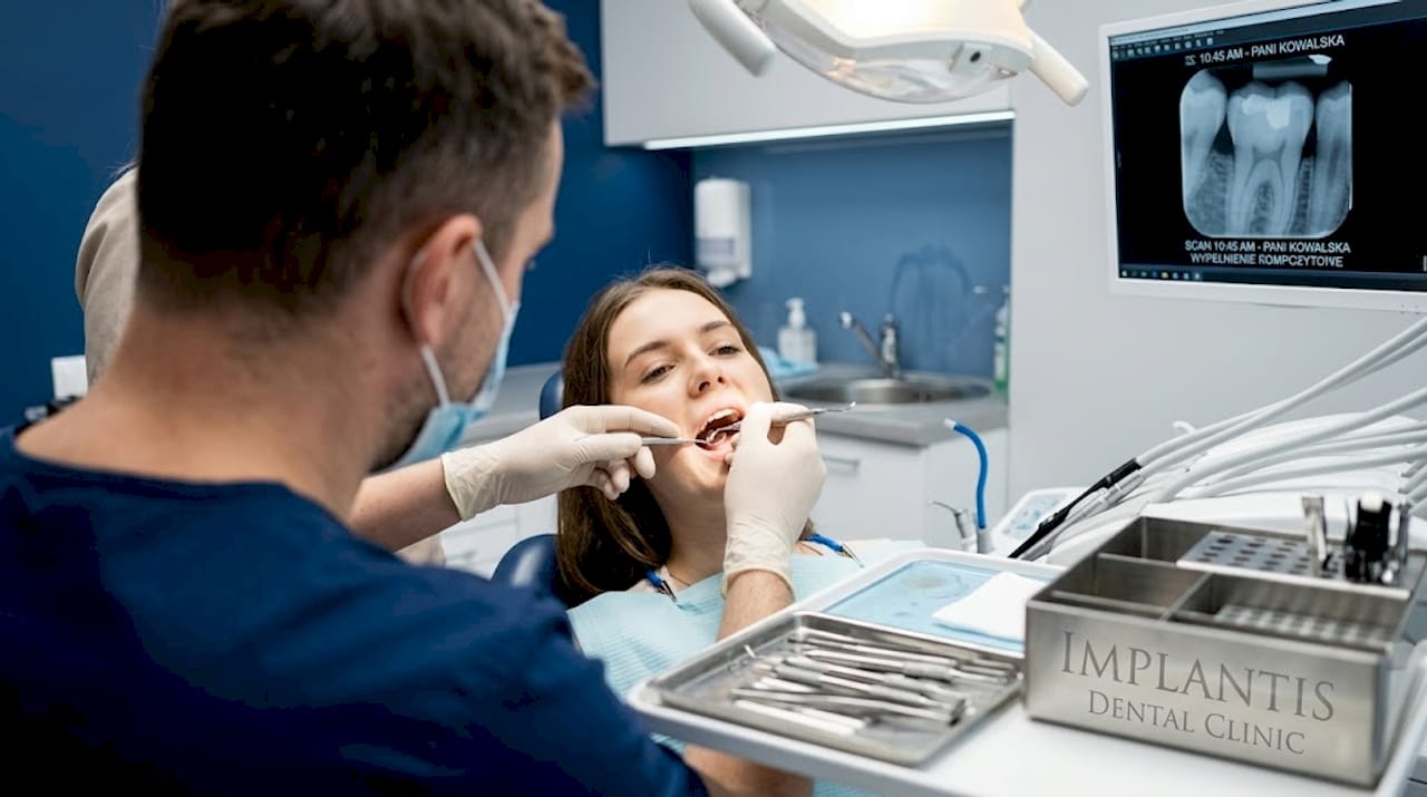 Stomatolog wraz z asystentką przeprowadzają zabieg wypełnienia ubytku.