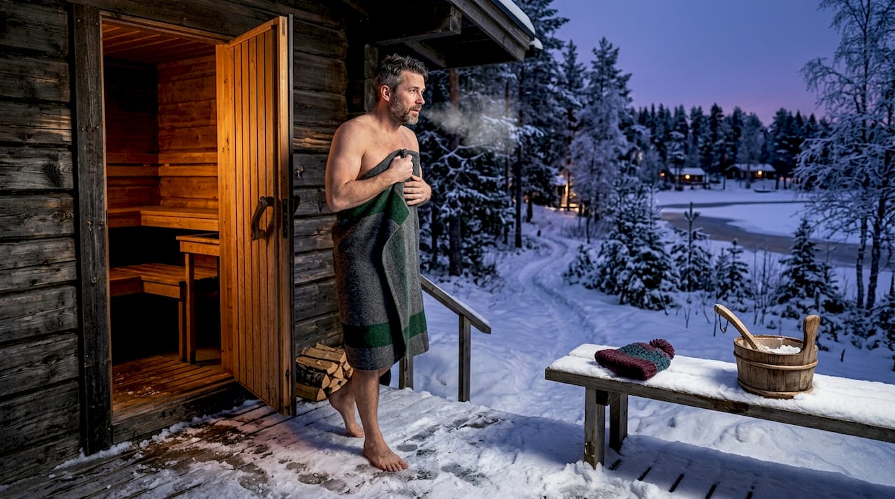 Man exiting sauna to snowy terrace in Lapland
