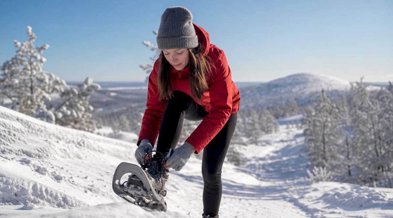 Woman adjusting snowshoes near Ukko-Luosto summit trail