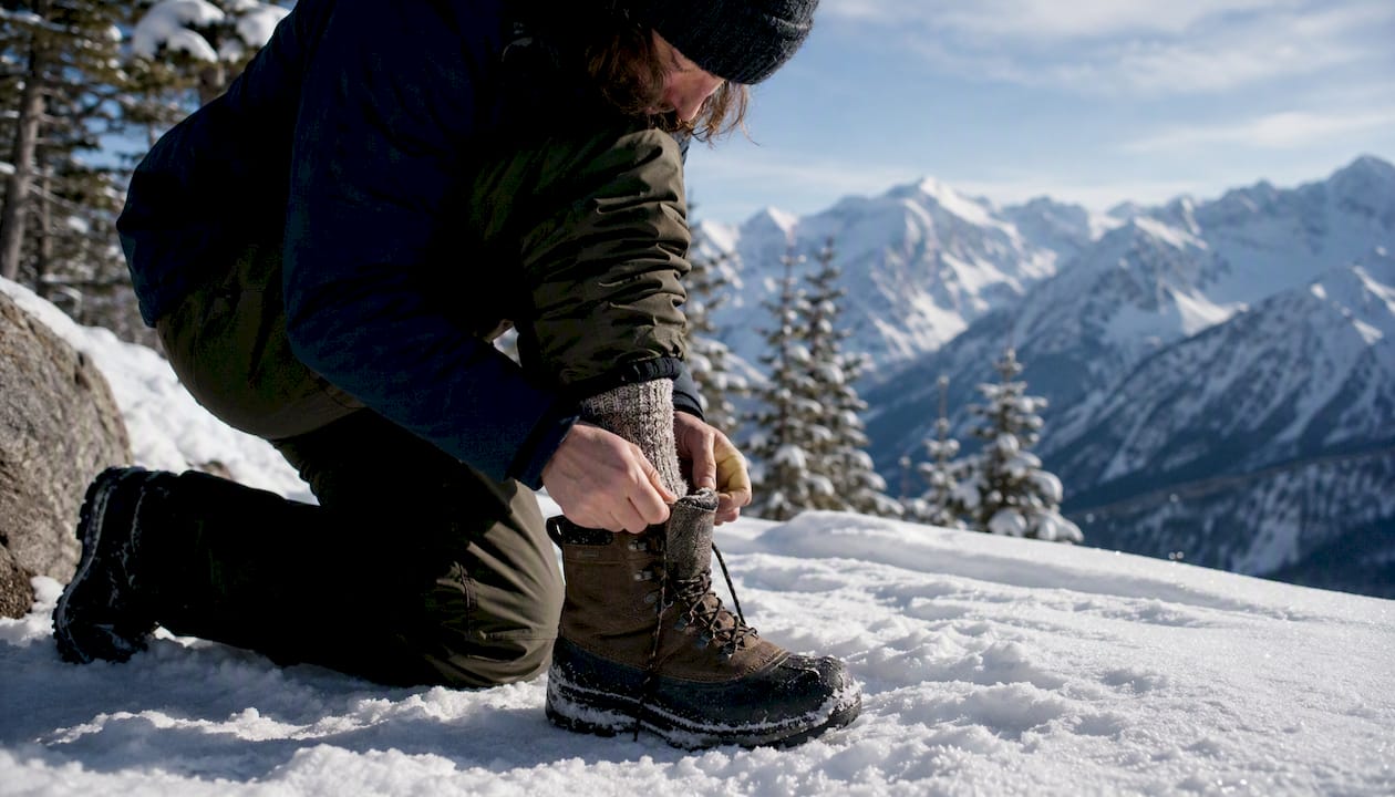 Hands adjusting wool sock inside winter boot