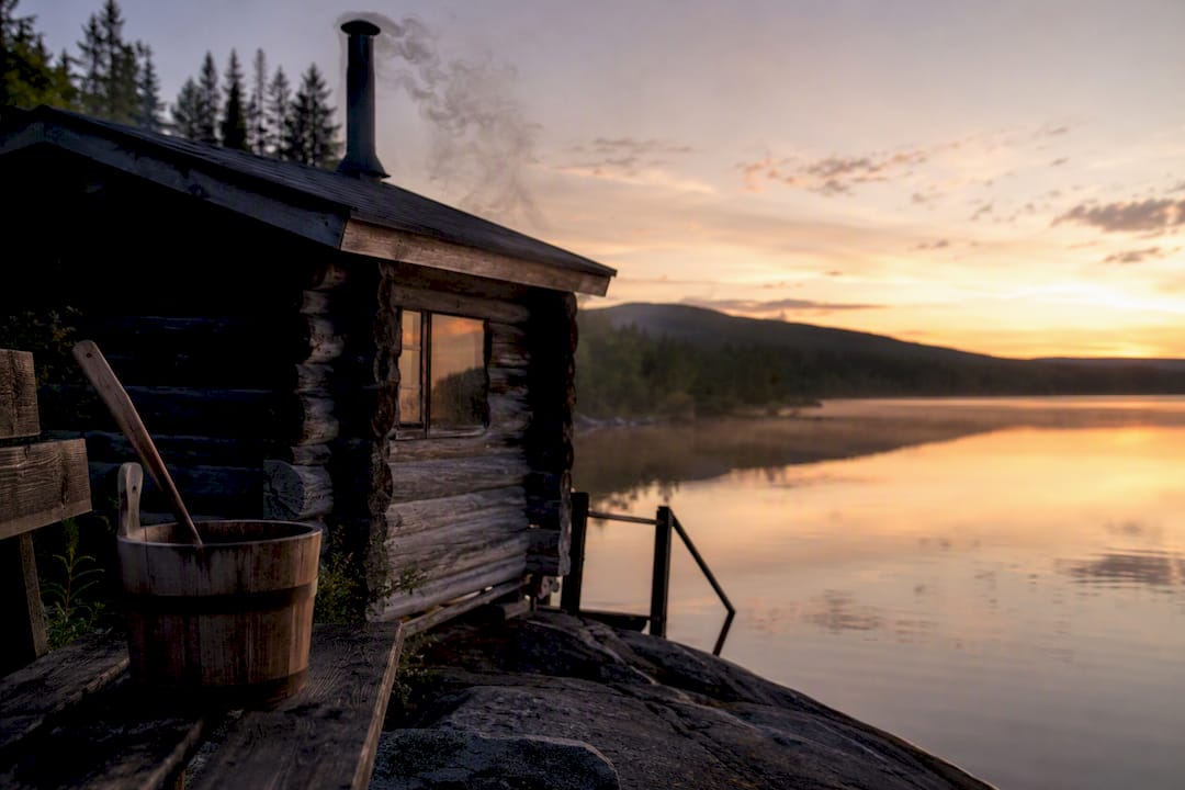 Finnish sauna cabin by lake with steam