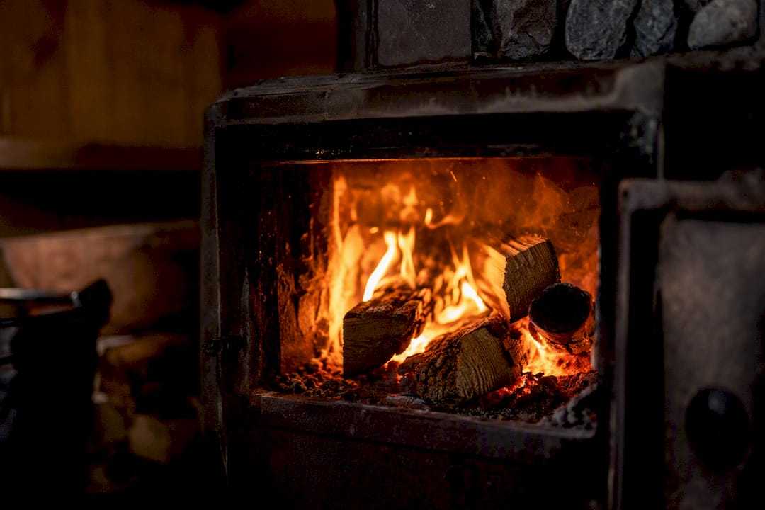 Glowing fire burning inside sauna stove