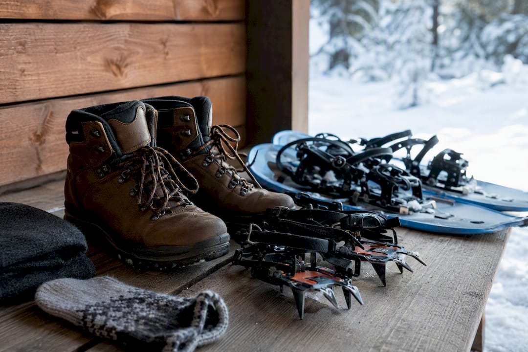 Hiking boots beside crampons and snowshoes