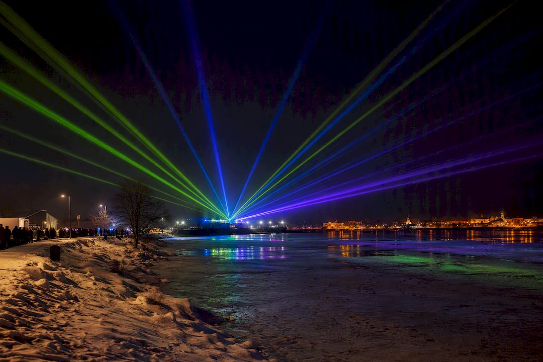 Laser beams over a snowy Finnish riverside