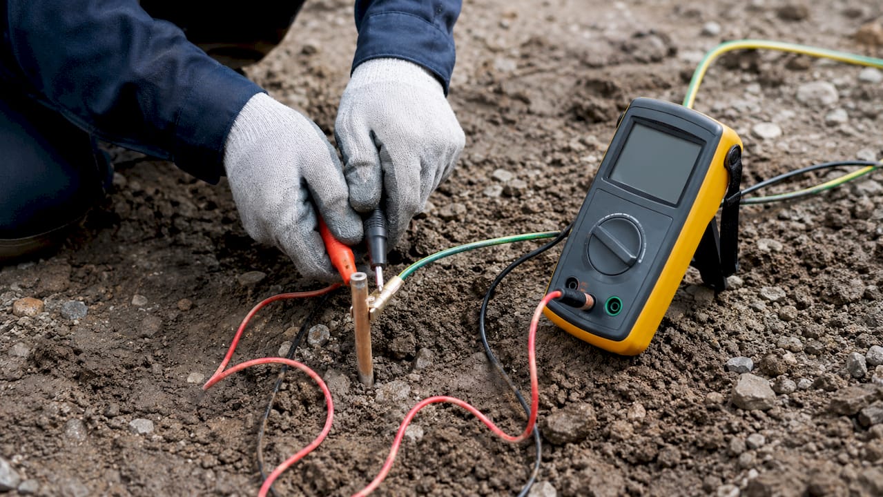 Un technicien effectue une mesure de la résistance de terre en extérieur.