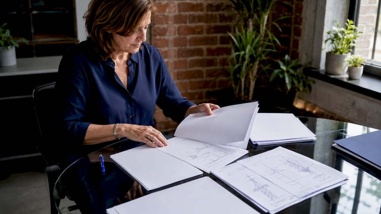Des mains en train de classer soigneusement les documents d’un dossier de certification