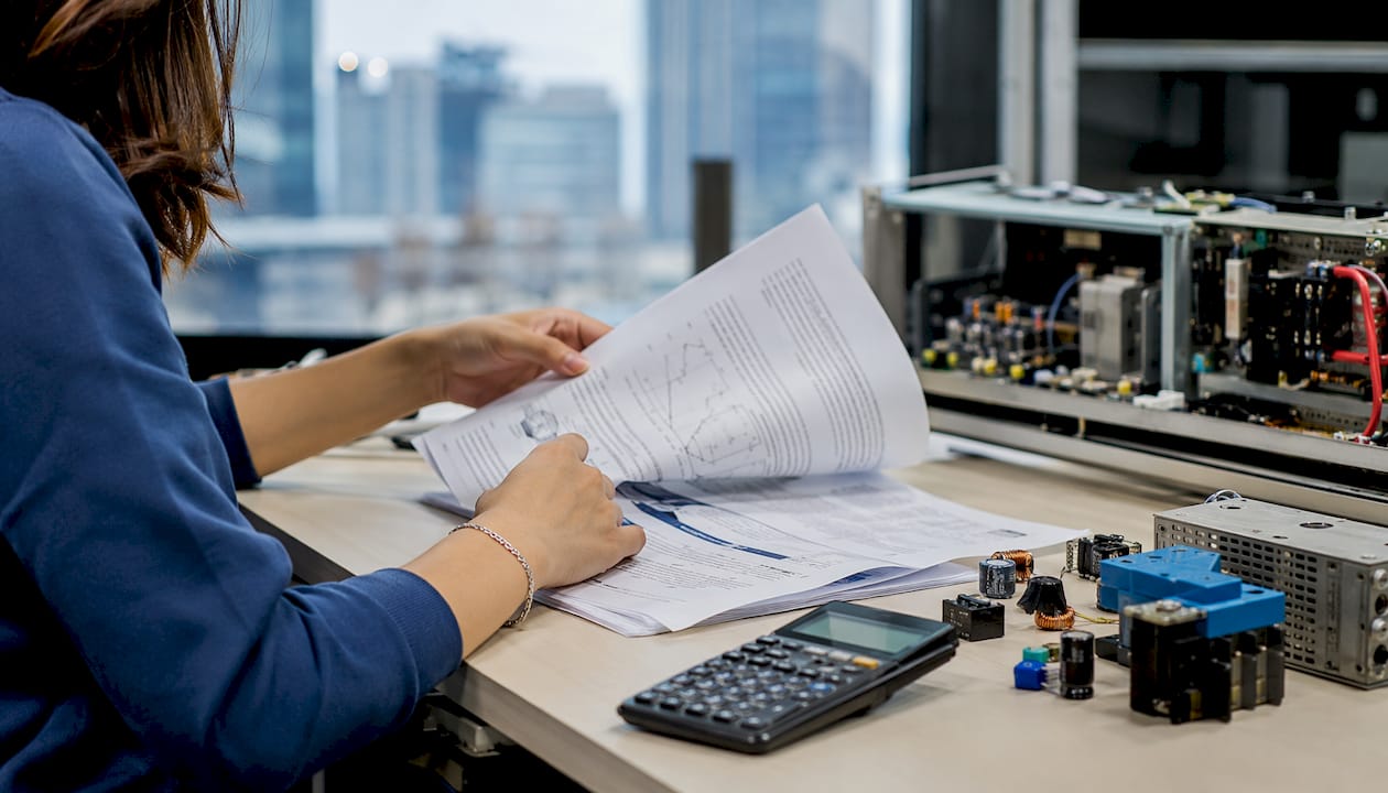 Close-up of hands reading electrical engineering papers