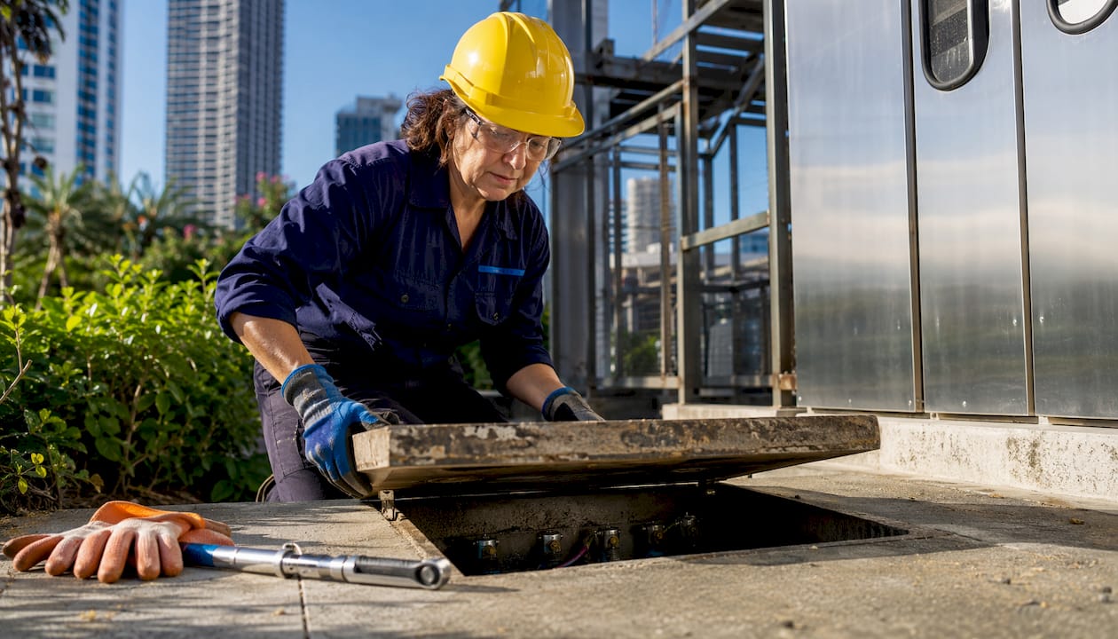 Technician opening earth pit at manufacturing site for maintenance