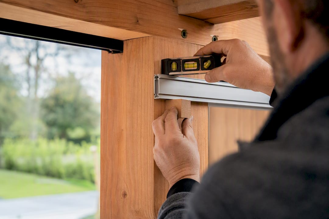 Monteur stelt de rail uit op een houten paal