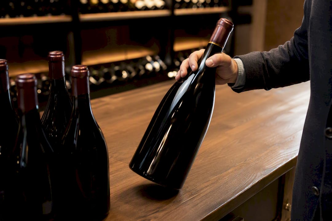 Hand placing magnum wine bottle on auction pallet