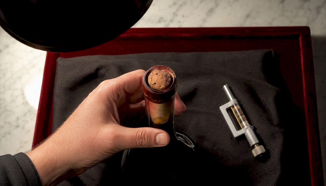 Specialist checking aged wine fill level and cork