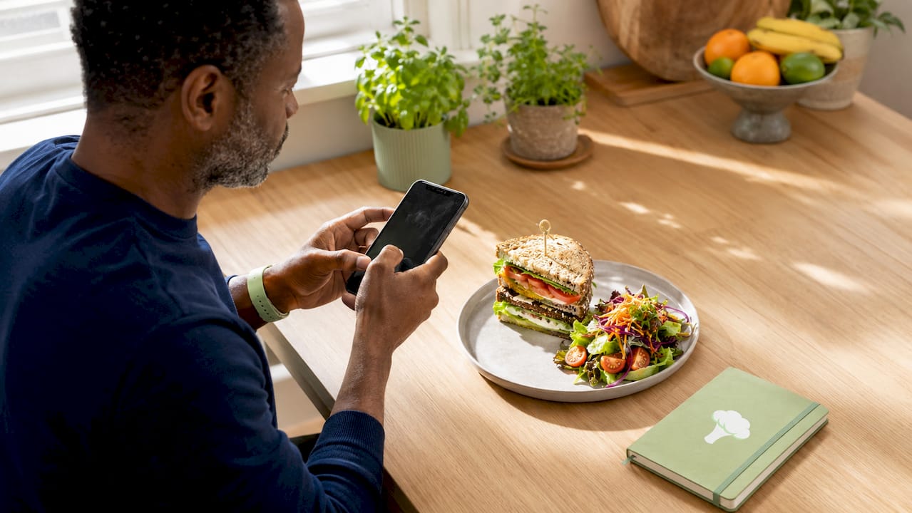 Close-up of hands photographing layered meal