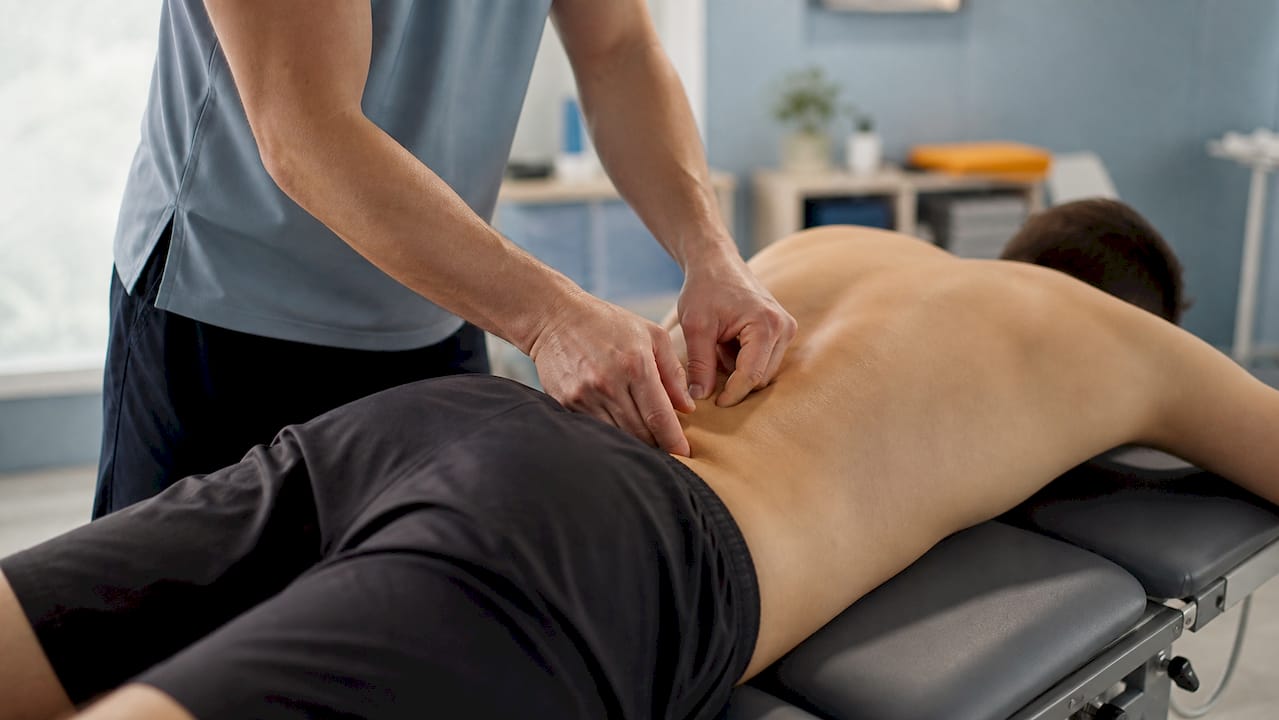 Hands applying manual therapy to lower back