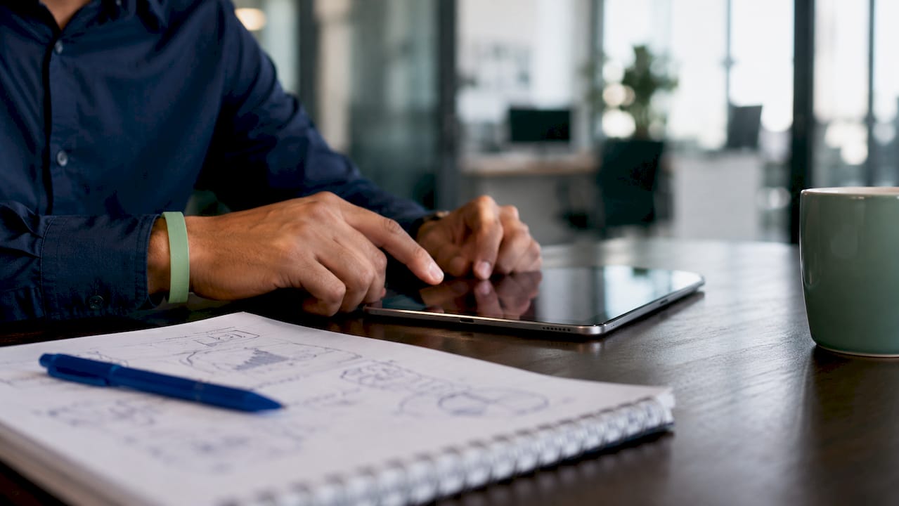 Personas tomando apuntes en una tablet durante una reunión en la sala de juntas