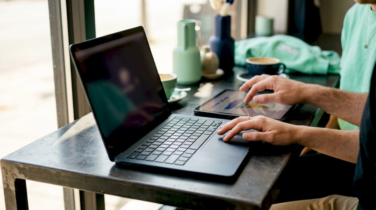 Personas gestionando información de clientes desde una tablet y un portátil