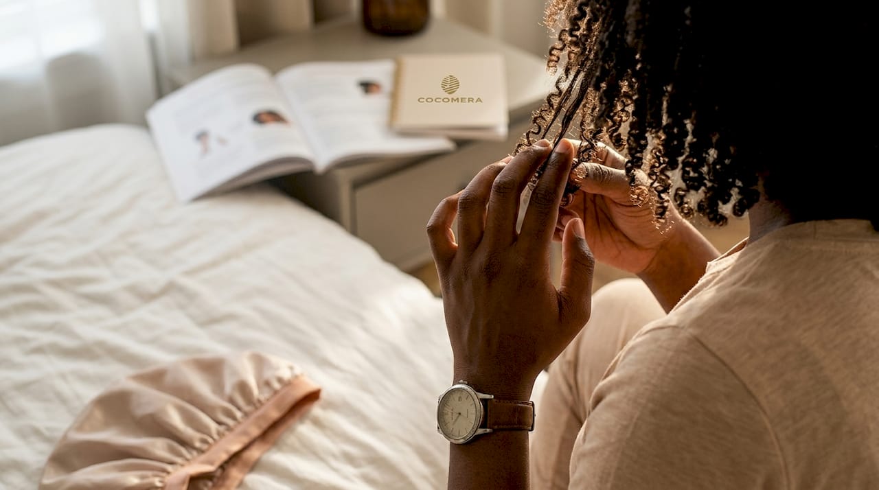 Hands checking soft, moisturized curls on bed