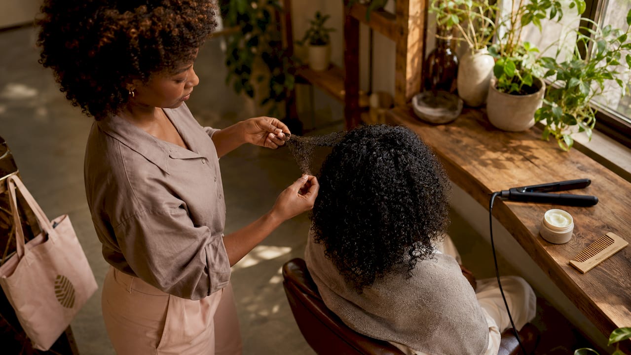 Stylist holding textured hair strand near flat iron