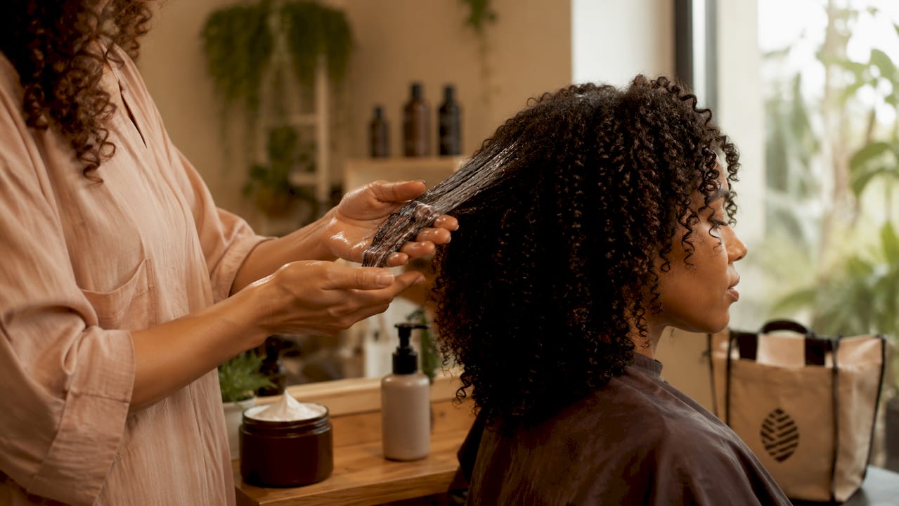 Stylist applying gel to curly hair section
